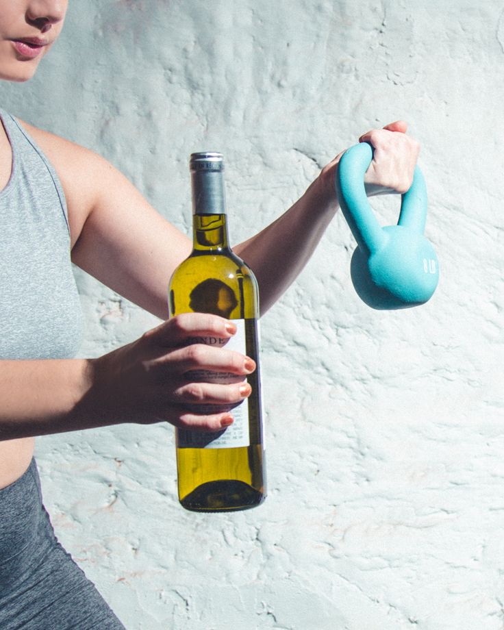 Slika sportiste koji u ruci drži čašu vina i razmišlja – kontrast između fit života i alkohola.